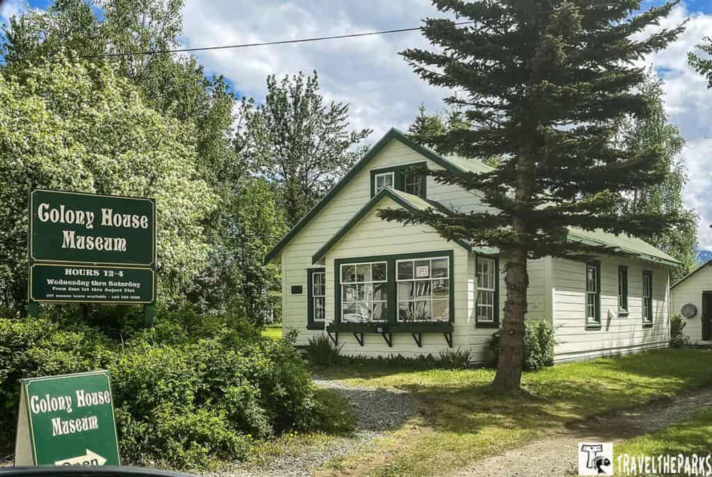 A white and green wooden building labeled as the Colony House Museum, surrounded by trees, with a sign indicating it is open.

