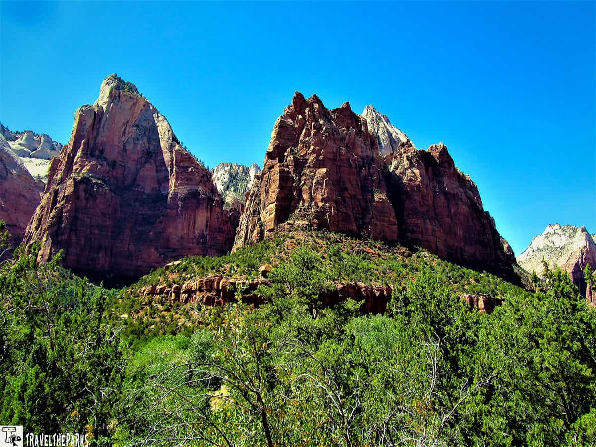 Court of the Patriarchs Viewpoint three towering sandstone peaks with lush green vegetation below at Zion National Park.