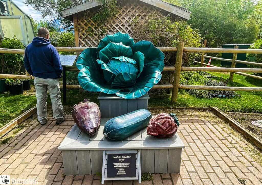 Oversized vegetable sculptures displayed in a garden setting.

