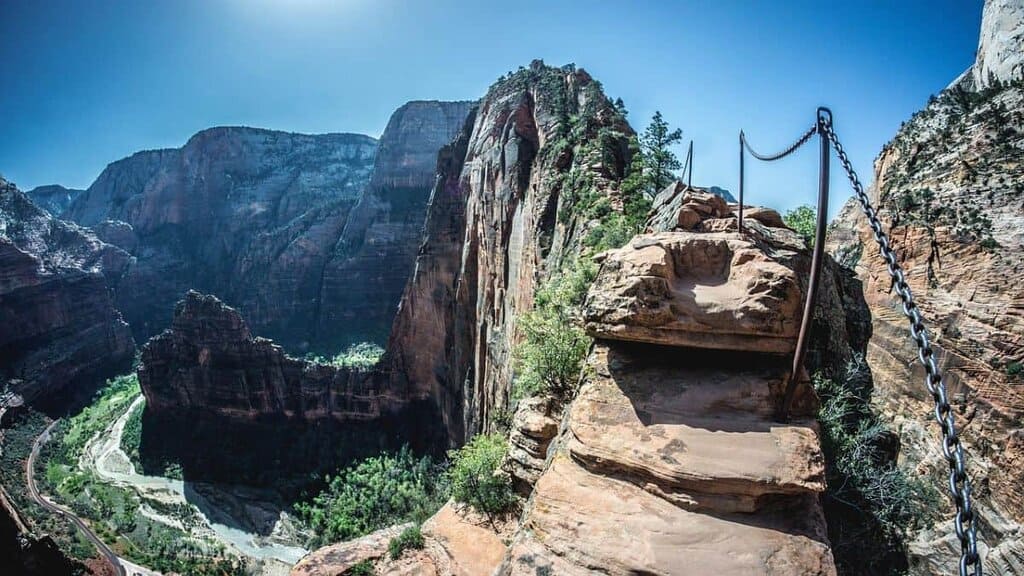 View from Angels Landing in Zion National Park with steep cliffs, a narrow trail, and a metal chain handrail.