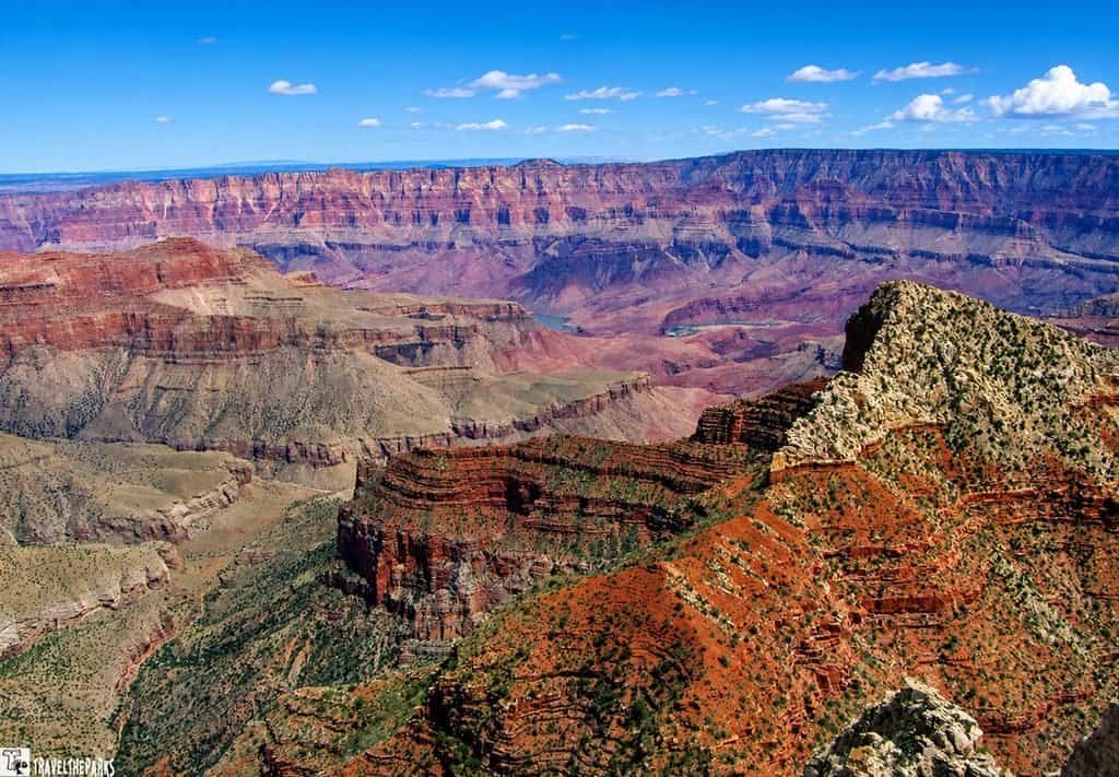 Freya's Castle-North Rim Grand Canyon: Panoramic Grand Canyon landscape with layered red-rock cliffs, deep canyon valleys, and a bright blue sky creating a vast, awe-inspiring view.

