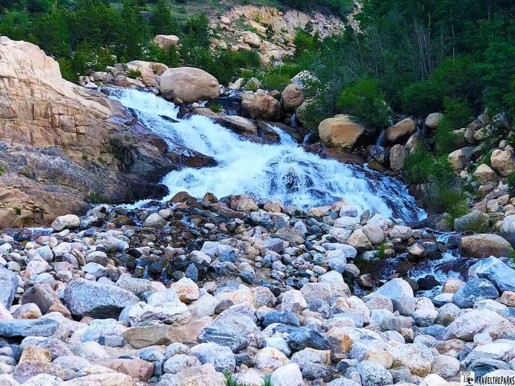 a rocky stream with clear running water and boulders on the bank
