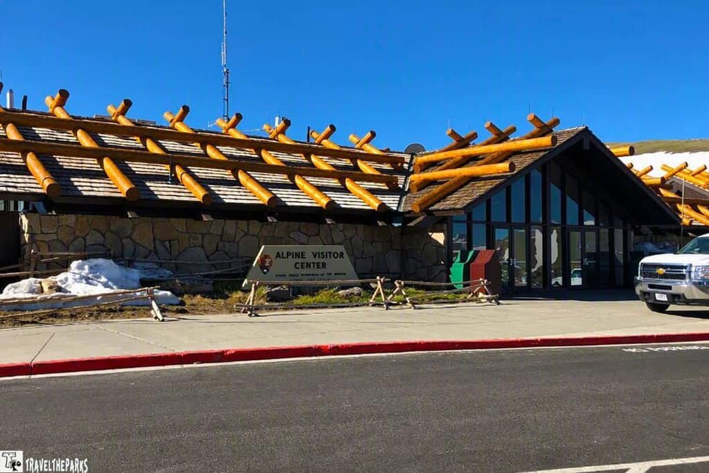Alpine Visitor's Center is a large building with a wooden roof set against the backdrop of Rocky Mountain National Park.