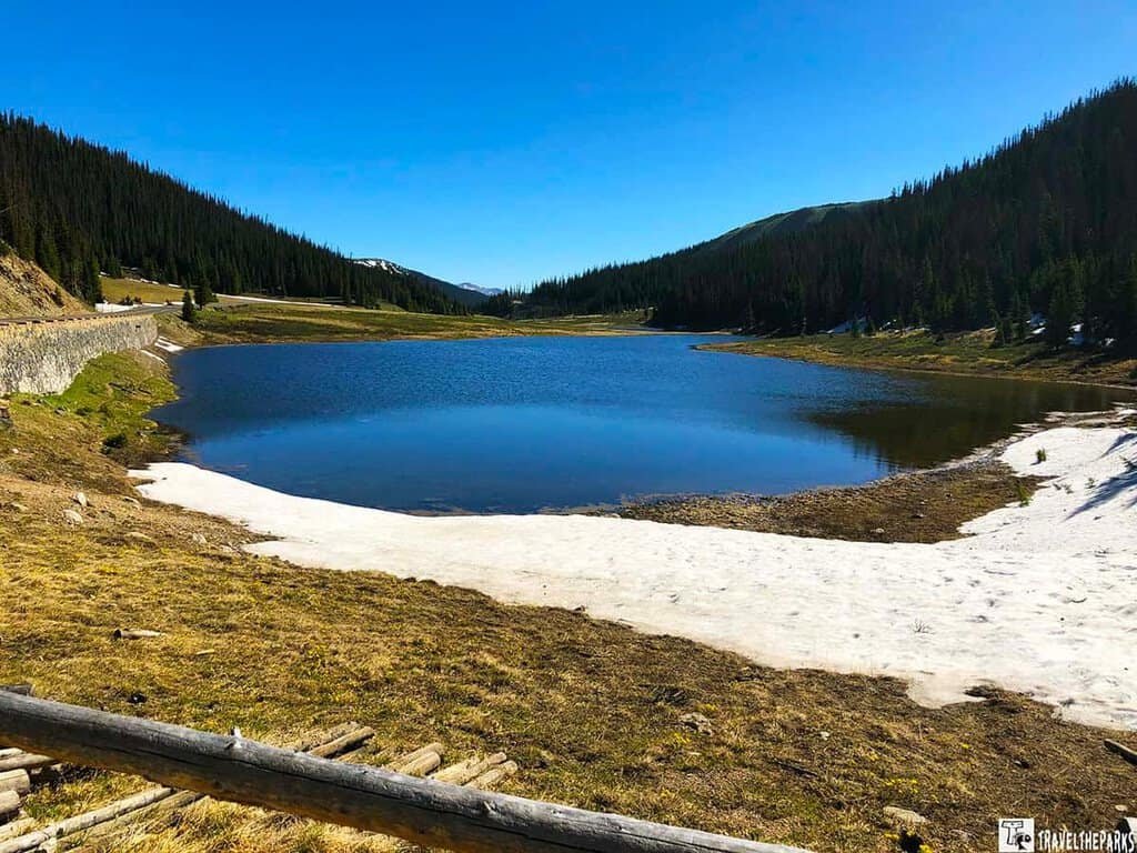 A picturesque Poudre lake in the Rocky Mountain National Park, framed by snow-dusted terrain and towering mountain peaks near Milners-Pass on the Trail Ridge Road