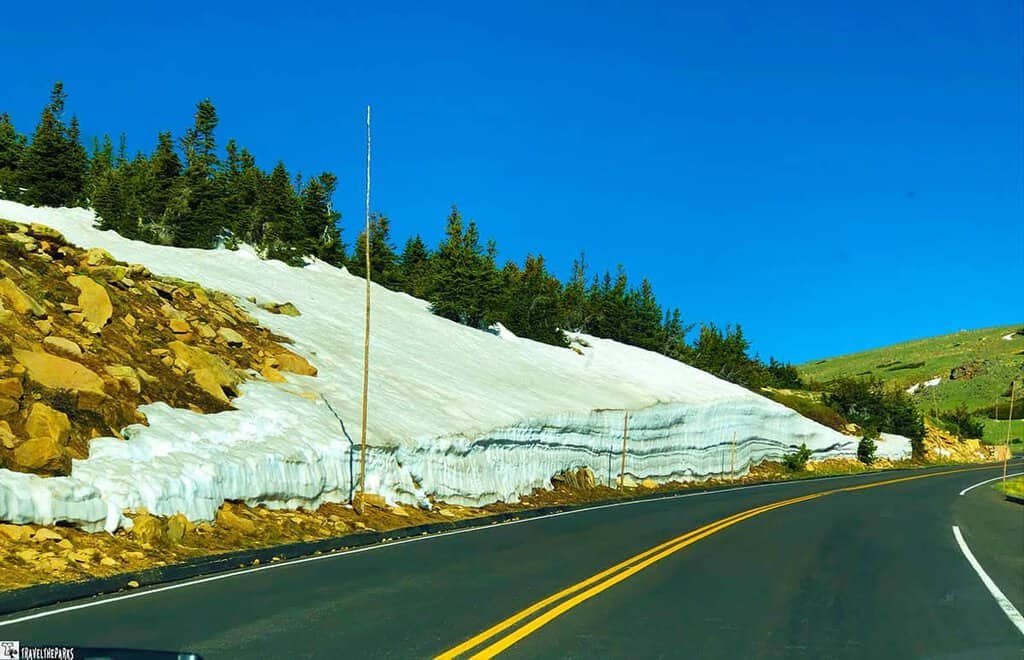 AT the Rock Cut a car navigates a snow-covered road in Rocky Mountain National Park, surrounded by majestic winter scenery of the Trail Ridge Road
