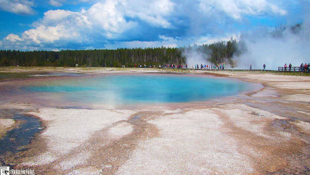Misty Turquoise Pool: A vibrant blue hot spring with steam rising, set against a backdrop of dense green forest and a cloudy sky. The scene conveys a serene, natural beauty.