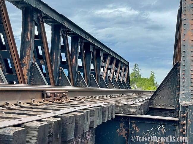 Railroad Bridge: Railway track on a rusted iron truss bridge extending into the distance.

