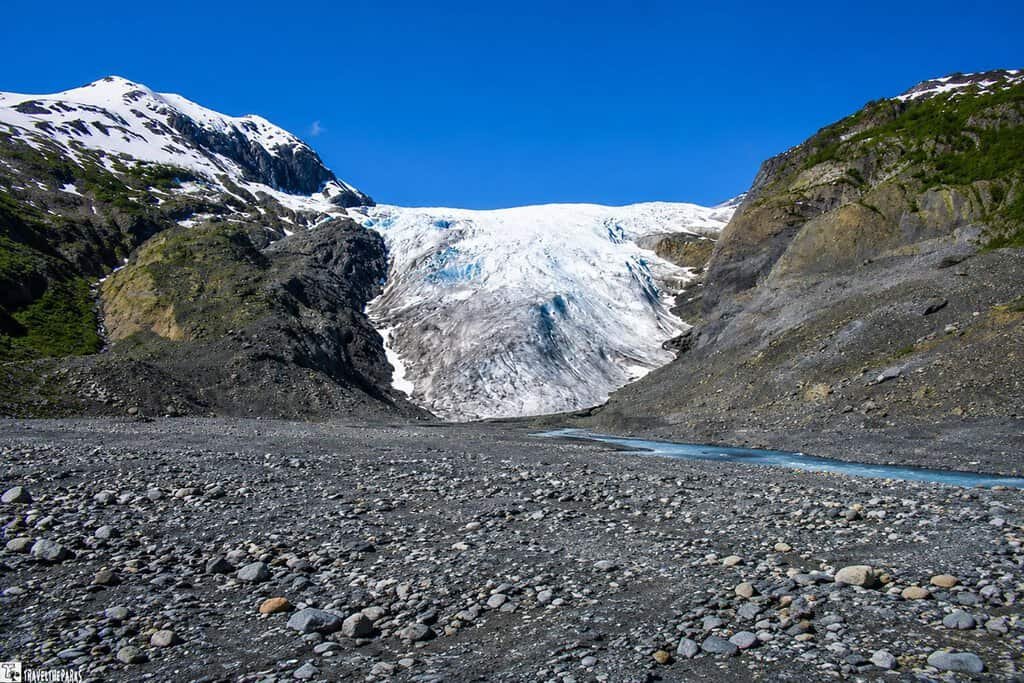 Toe of the Exit Glacier with rocky terrain under a clear blue sky.