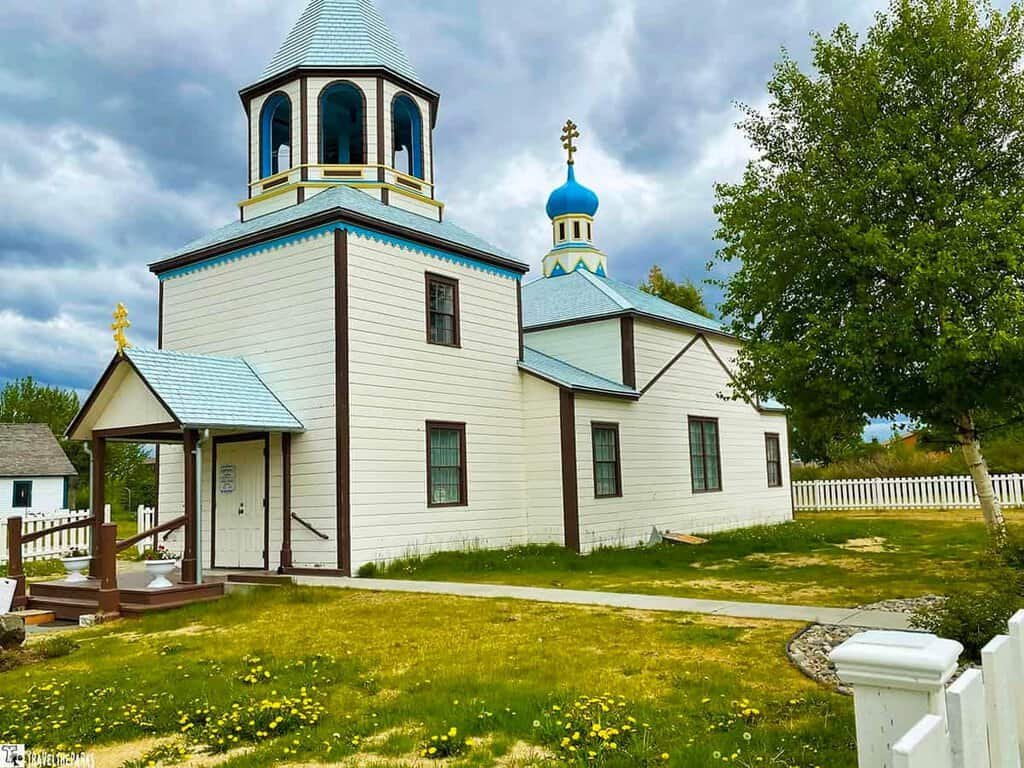Holy Assumption of Saint Mary Russian Orthodox Church: White and blue traditional church with onion dome and picket fence under cloudy sky.