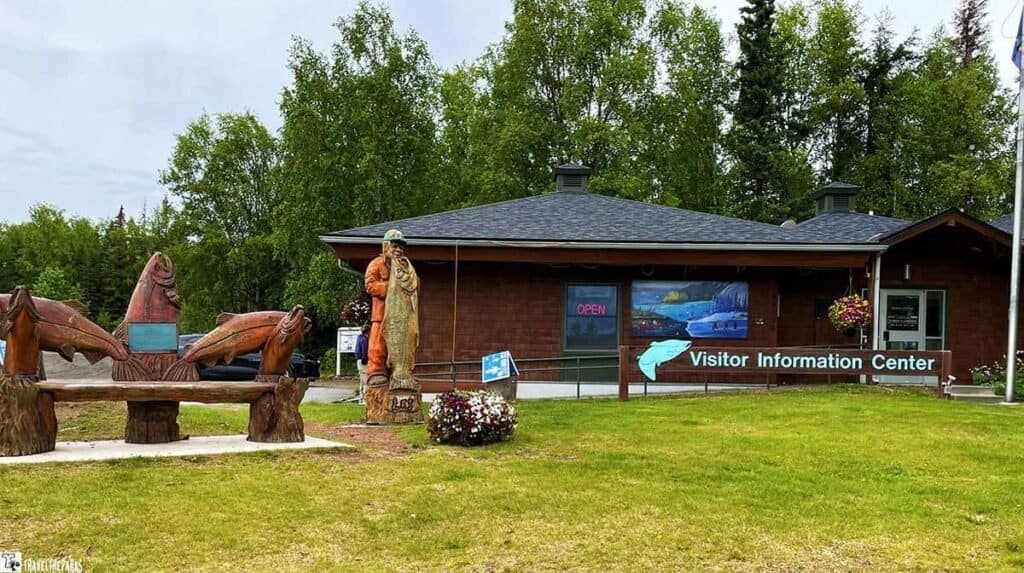 Visitor Information Center with wooden carvings and a grassy foreground.