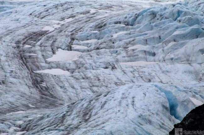 Close-up of Exit Glacier with blue and white ice and dark streaks.