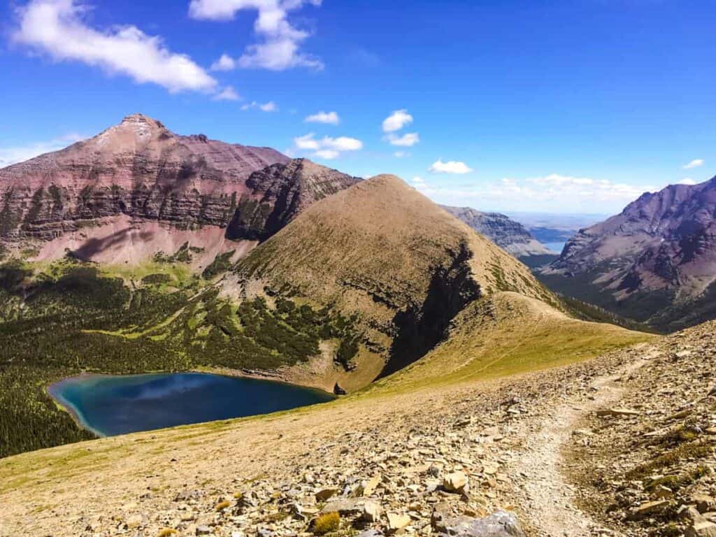 A scenic view of Glacier National Park featuring a lake, mountainous ridges, and a clear blue sky.