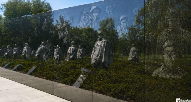 Korean War Veterans Memorial with soldier statues and reflective wall etched with faces.