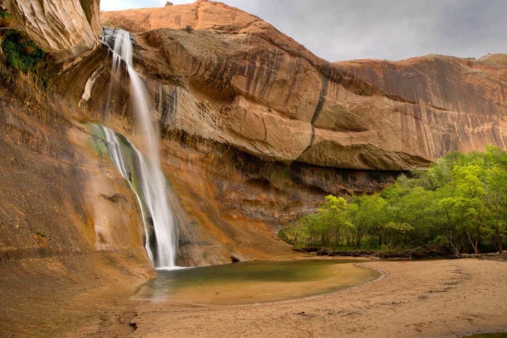 Lower Calf Creek Trail waterfall at Grand Staircase-Escalante National Monument flowing down a textured rock face into a pool.