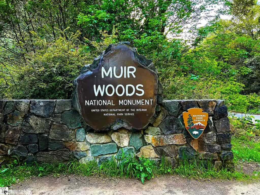 Entrance sign to Muir Woods National Monument with surrounding greenery.