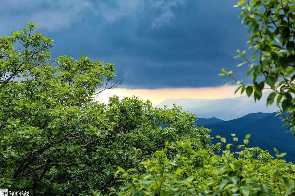 America's National Park view of lush green trees and blue mountains under a stormy sky with a light horizon in Shenandoah National Park.