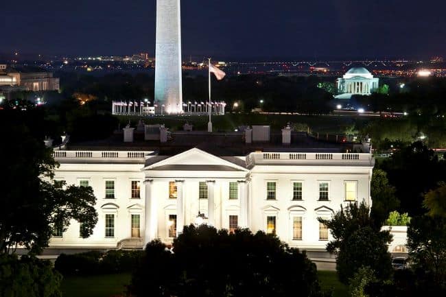 Washington DC The White House illuminated at night with an American flag flying above.