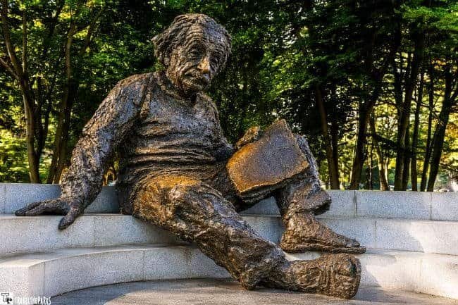 National Academy of Sciences-Bronze statue of a seated Albert Einstein figure holding a book on a circular stone platform.