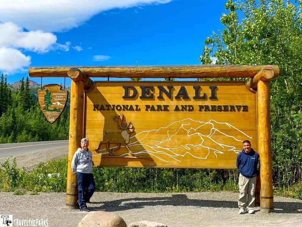 Sign for Denali National Park and Preserve with people standing in front.