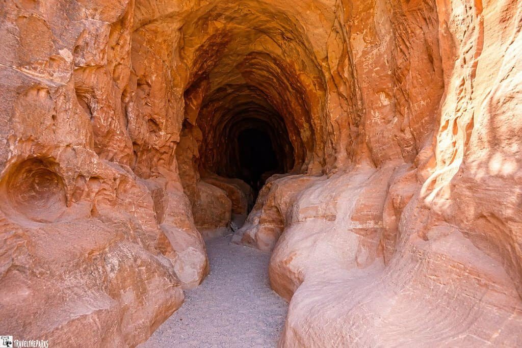 A natural cave with smooth, textured rocky walls in earthy tones, extending into darkness