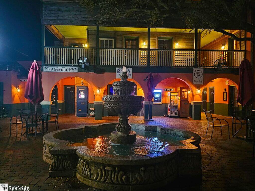 Nighttime courtyard with a lit fountain, archways, and signs for "Old City Hammocks" and "BHN 39 Wine Bar."

