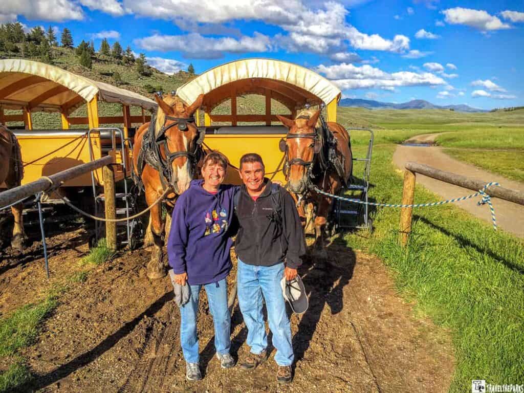 Old West Dinner Cookout: A woman and a man standing in front of two horses hitched to a wagon in a scenic outdoor setting.