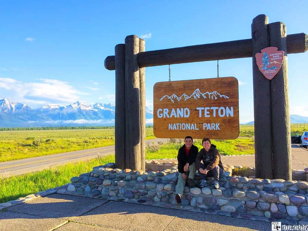Grand Teton National Park entrance sign with mountains in the background.