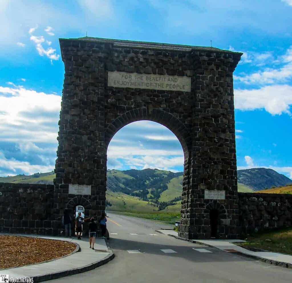 Roosevelt Arch with a scenic background of hills and sky.

