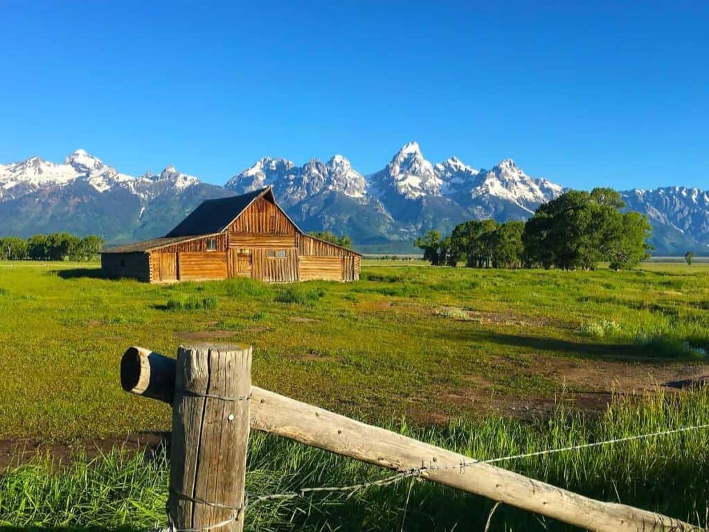 Moulton Barn with Grand Teton mountains in the background under a clear blue sky.

