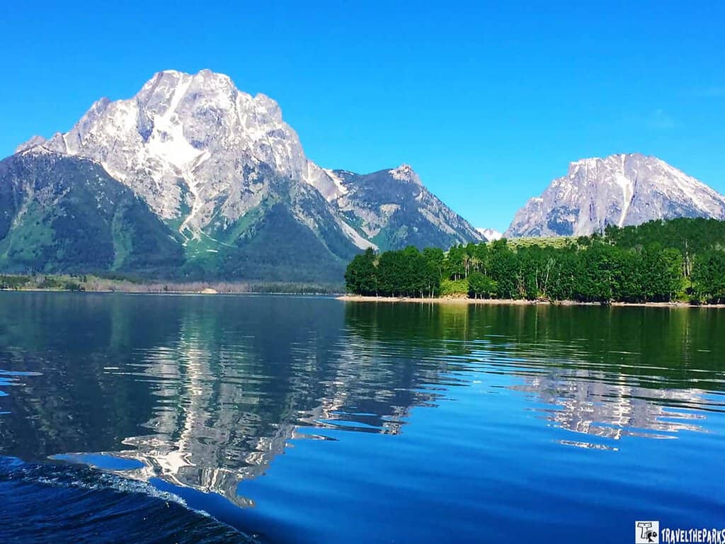 Mount Moran-Jackson Lake-Mountain landscape reflected in a calm lake with foam patterns in the water.