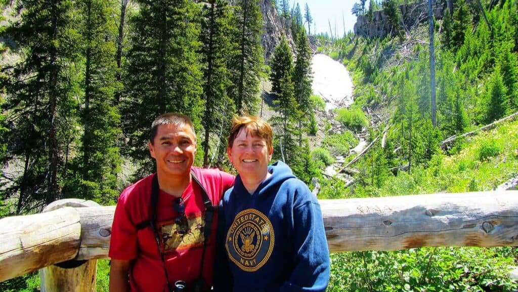 Two people smiling in a forest setting with Wraith Falls in the background.