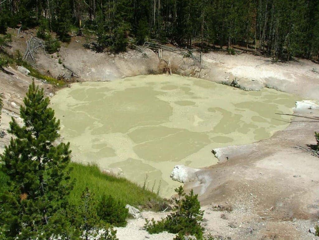 Geothermal mud pool emitting steam in a rocky landscape-Mud Volcano Yellowstone National Park