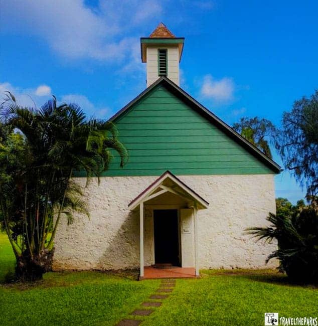 Palapala-Hoomau-Church: A small building with a green and stone exterior, featuring a gabled roof and bell tower, set on a grassy lawn with palm trees.