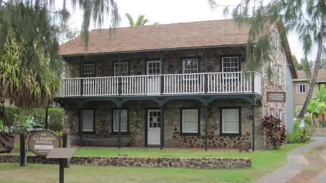 Historic stone building with a white-balustrade balcony, known as U.S. Seamen's Hospital in Maui.
