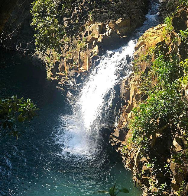 On the Road to Hana Pua'a Ka'a State Wayside & Falls cascading into a rocky pool surrounded by greenery.