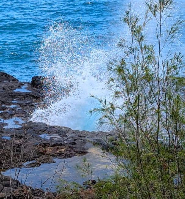 Seawater sprays from Nakalele Blowhole, surrounded by rocky coast and ocean backdrop in Maui Hawaii 