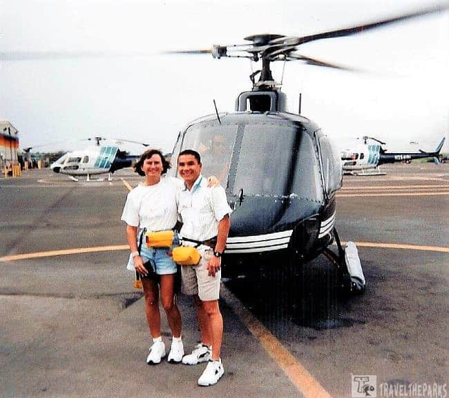 Sunshine Helicopters Tour: Two people standing in front of a helicopter at a helipad.