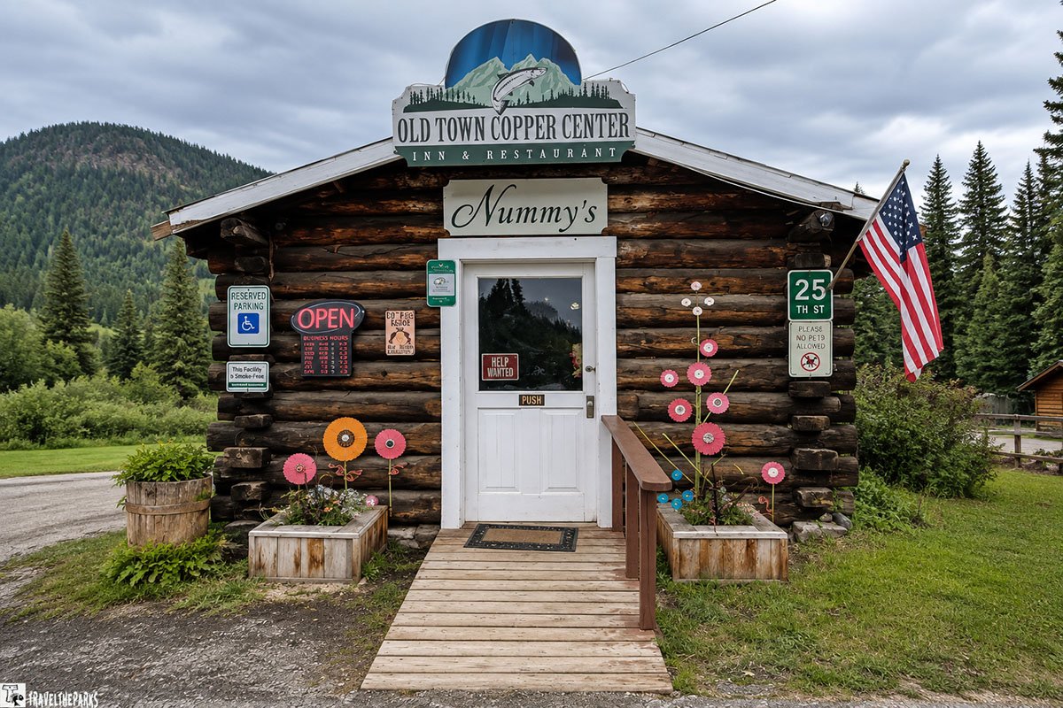 Entrance of Old Town Copper Center Inn & Restaurant with "Nummy's" sign, surrounded by decorative elements and various signs.