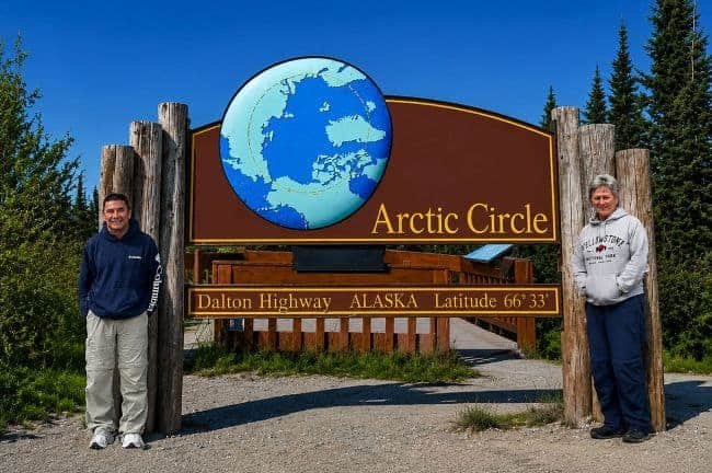 Dalton Highway Arctic Circle Sign with two people standing in front