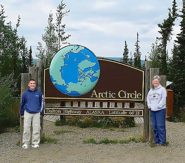 Dalton Highway Arctic Circle Sign with two people standing in front
