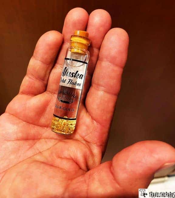 Gold flakes in a vial in the palm of a hand