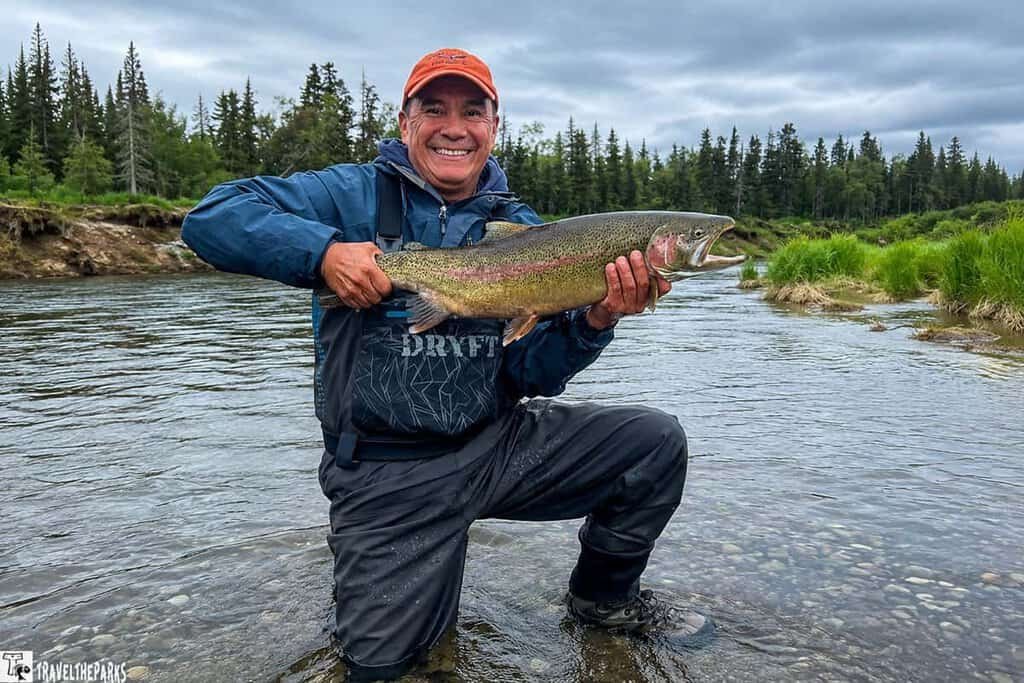 A man holds a Trophy Rainbow from the Brooks River