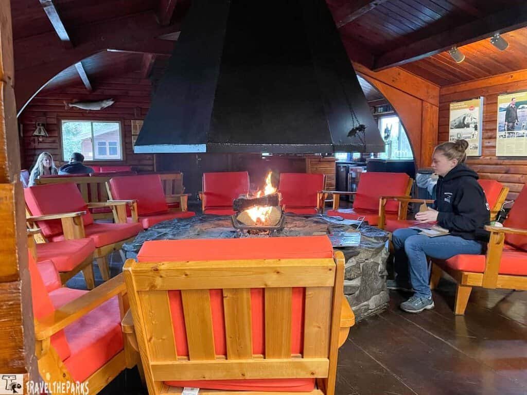 Firepit at the Brooks Camp Dining Lodge: A cozy room with a stone fireplace and red-cushioned chairs.