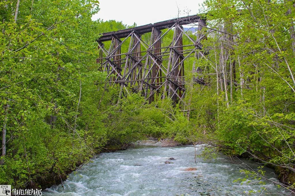 Glahina Trestle McCarthy Road: A wooden railway bridge surrounded by green foliage and a gravel road in the foreground.
