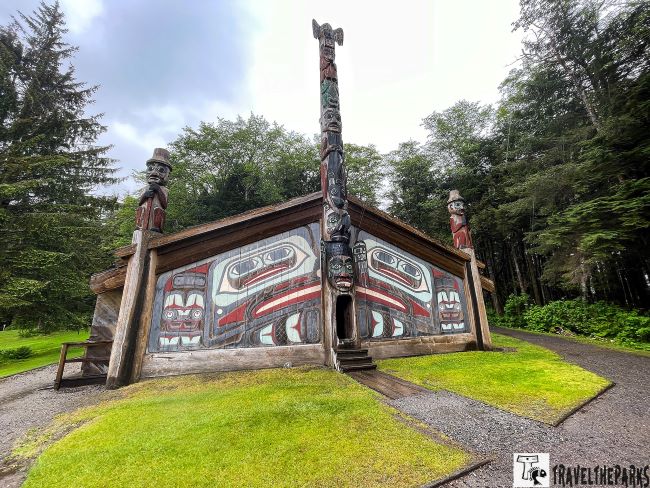 Tinglit Clan House wooden structure with totem poles and vivid Indigenous art at Totem Bight Historical State Park