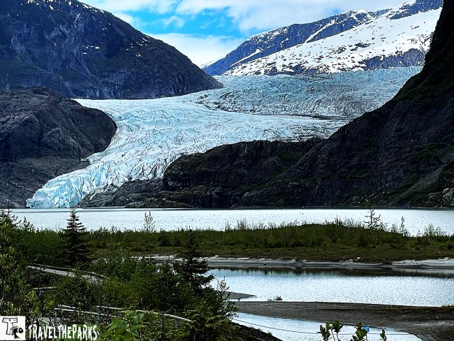 Mendenhall Glacier with surrounding mountains and a lake in the foreground.