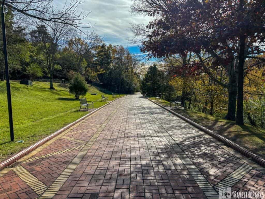 A brick pathway of the Grand Promenade Hot Springs National park surrounded by autumn trees and benches.