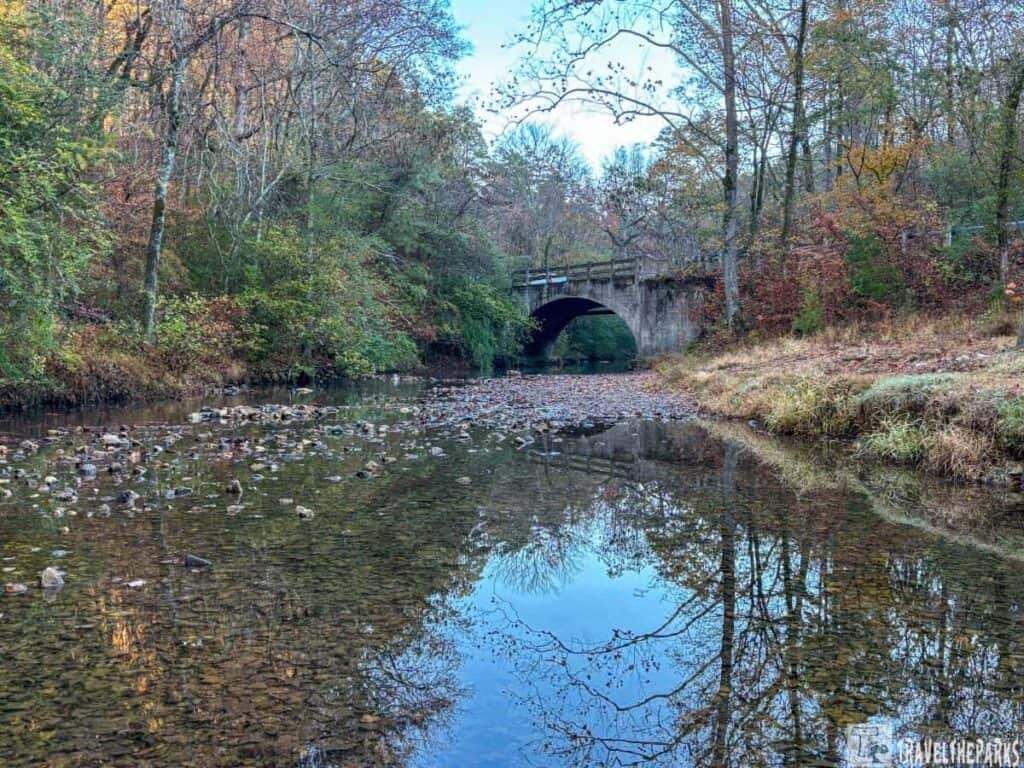 Gulpha Gorge Creek with an arched stone bridge, surrounded by autumn trees.