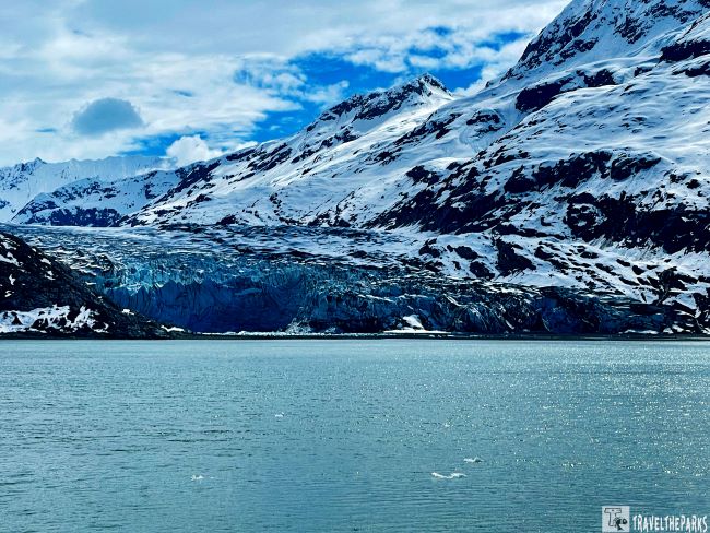 Johns Hopkins Inlet with snow-capped mountains and a Lamplugh glacier above light blue water.