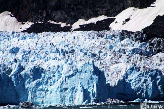 Blue Margerie glacier with rocky mountains and snow in the background.